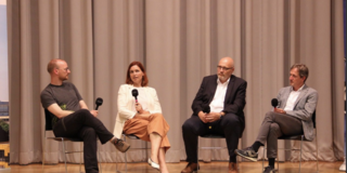 Four people having a conversation on stage while holding microphones
